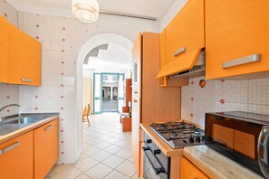 Eine Küche mit orangenen Schränken, einem Gasherd und einer gefliesten Spritzschutzwand.