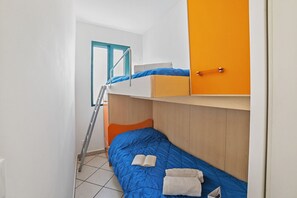 Ein Schlafsaalzimmer mit Etagenbetten, einer Leiter, einer Tür und einem Fenster.