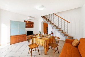 Ein Essbereich mit einem Tisch für vier Personen, einer Couch und einer Treppe.