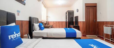 A hotel room with two beds, a wooden wardrobe, a television, and a framed picture on the wall.