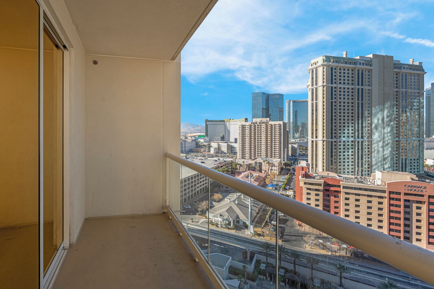 Un balcon offrant une vue sur la ville, avec de hauts immeubles en contrebas et un ciel dégagé.