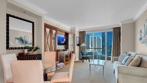 A modern living room with a dining area, a sofa, a TV, and a view of the cityscape. - Corner Suite with Strip View, F1, Balcony at MGM Signature, NO Resort Fee - 1621 (Las Vegas)