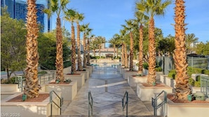 A pathway lined with palm trees leading to a building with a glass facade. - Corner Suite with Strip View, F1, Balcony at MGM Signature, NO Resort Fee - 1621 (Las Vegas)