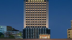 Een hoog hotelgebouw met meerdere verdiepingen en een opvallend bord bovenaan.