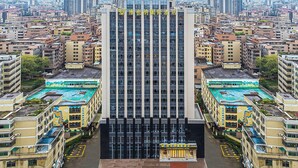 Een hoog hotel met een centrale ingang, omringd door andere gebouwen.