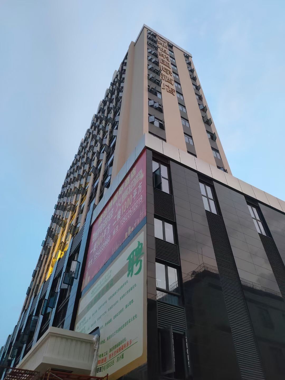 Un edificio alto con varios pisos, ventanas amplias y un letrero llamativo en la fachada.