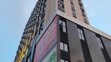 Un edificio alto con varios pisos, ventanas amplias y un letrero llamativo en la fachada.