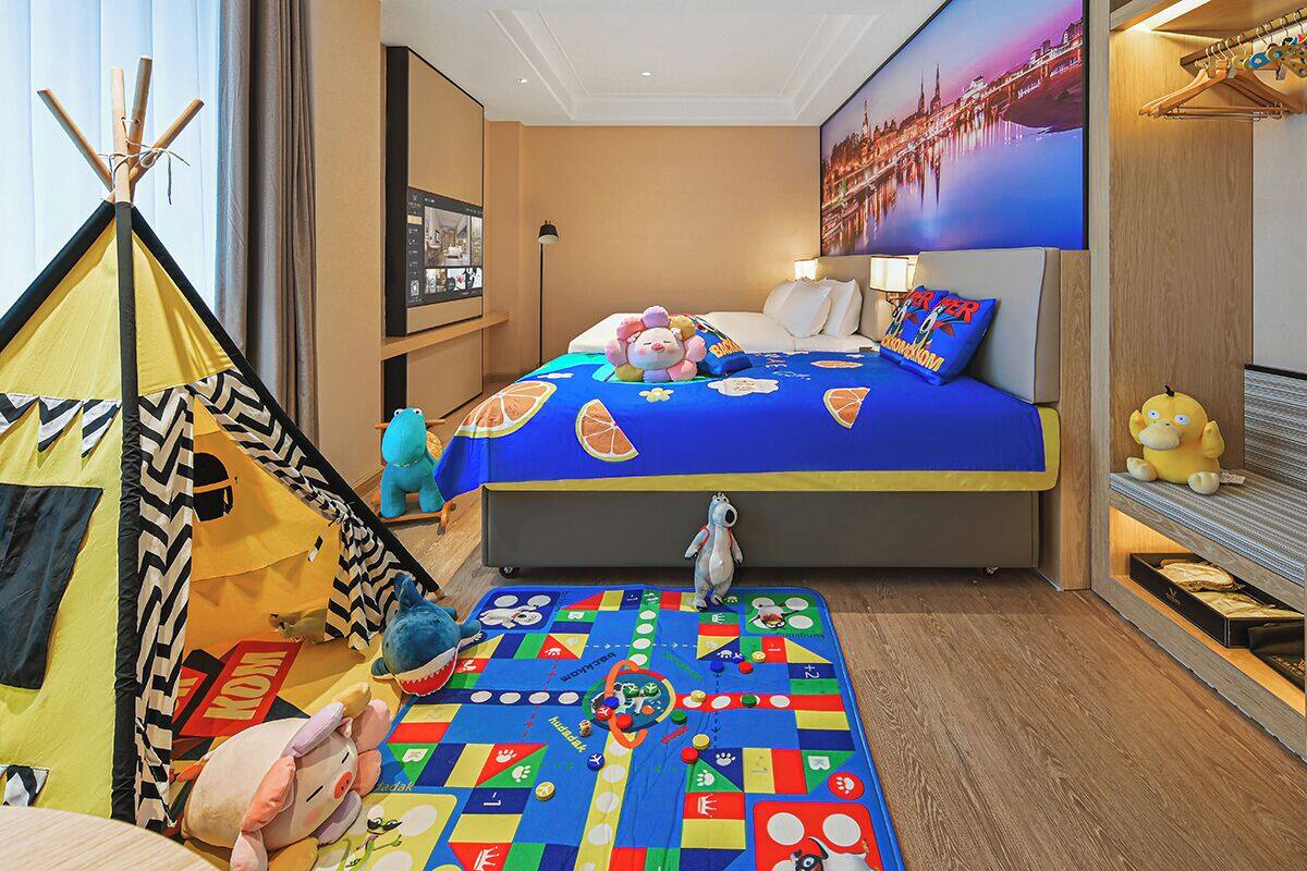 Ein Hotelzimmer mit einem Bett, einer bunten Spielecke, einem Teepee und verschiedenen Stofftieren.