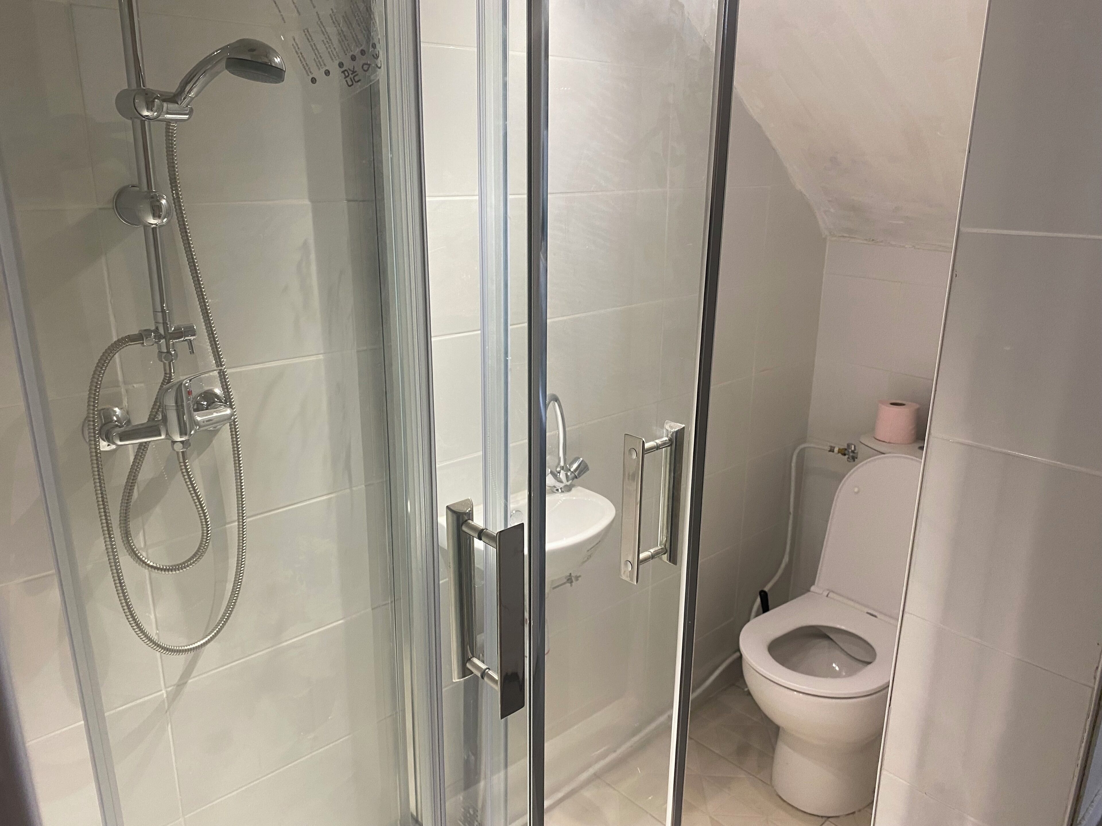 Ein modernes Badezimmer mit einer begehbaren Glasdusche, einem weißen Waschbecken und einer Toilette.