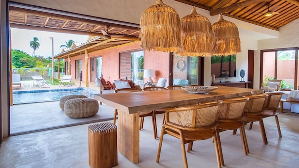 A spacious dining area with a large wooden table, wicker chairs, and hanging wicker lamps. - Casa com Piscina e Quadra no Condom nio By Toque (São Miguel dos Milagres)