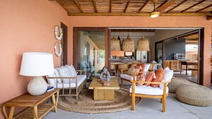 A cozy outdoor seating area with wicker furniture, a wooden table, and a large lamp. - Casa com Piscina e Quadra no Condom nio By Toque (São Miguel dos Milagres)