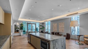 A modern kitchen with a marble island, wooden cabinets, and a built-in oven. - Downtown Miami Worldcenter Studio, Pool & Balcony (Miami)