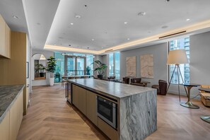A modern kitchen with a marble island, wooden cabinets, and a built-in oven. - Modern Miami Studio | Balcony, Rooftop Pool & Gym (Miami)