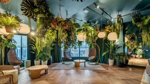 A room with hanging plants, a round wooden table, and wicker chairs. - Downtown Miami Worldcenter Studio, Pool & Balcony (Miami)