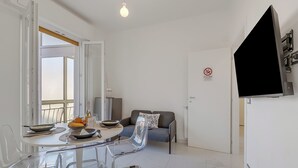 Una sala de estar moderna con una mesa de comedor, sillas, un sofá y un televisor montado en la pared.