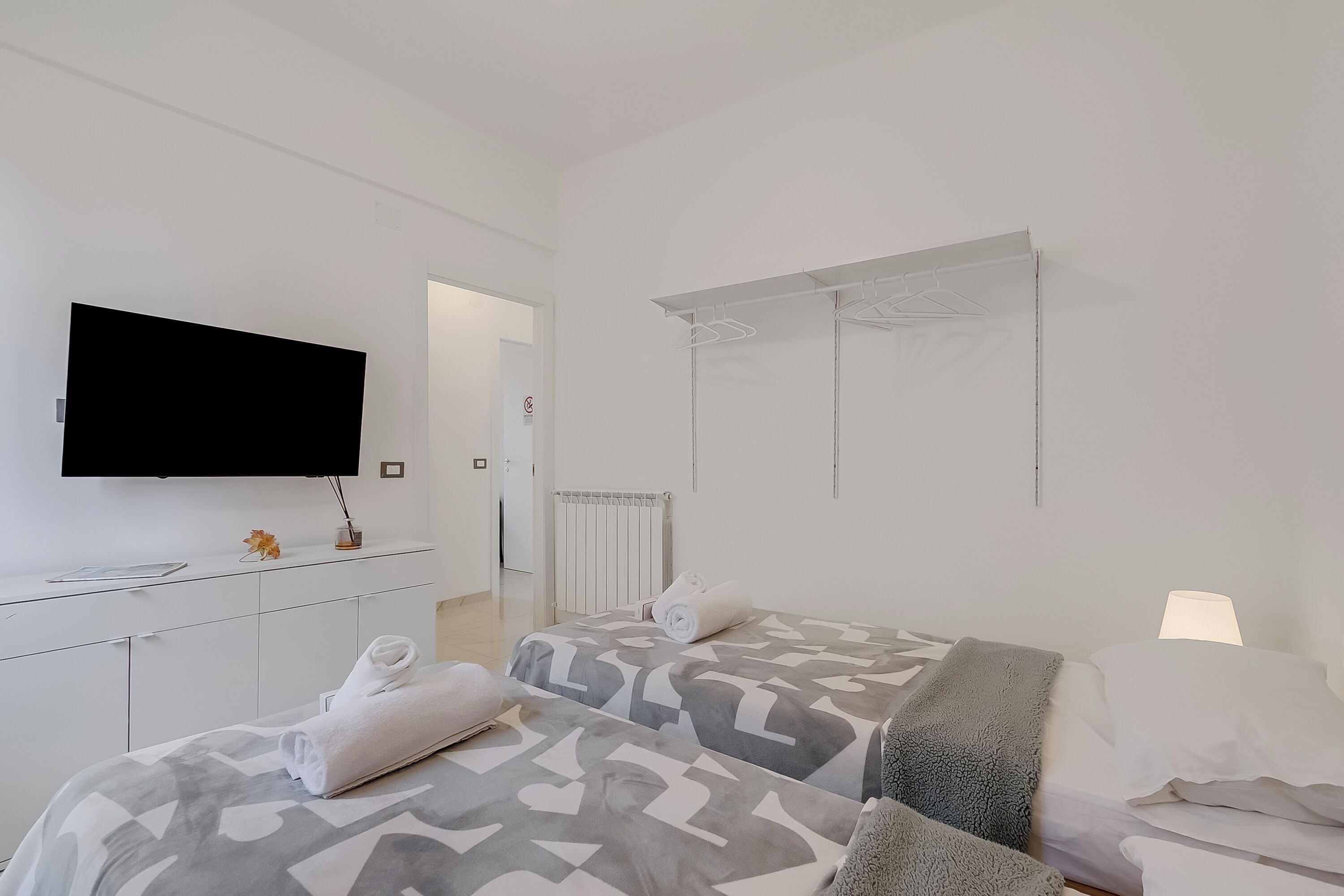 A hotel room with two beds, a TV, a desk, and a wardrobe.