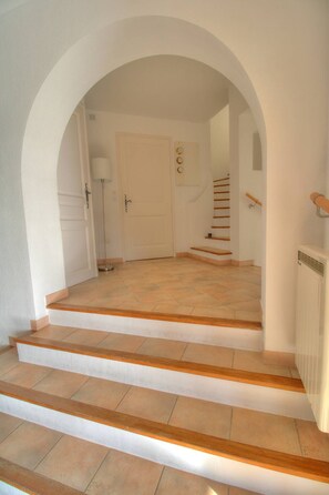 Eine Treppe mit Holzdielen und beigen Fliesen, die zu einem Raum mit einer weißen Tür und einer Lampe führt.