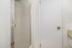 A bathroom with a glass shower door, white walls, and a visible light switch. - 3BR/3BA Private Suites Home / Llano & Wind Crew Ready / Fast WiFi & 2 Car Garage (Amarillo)