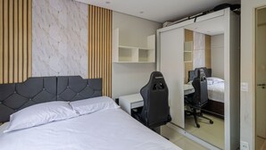 Een moderne hotelkamer met een bed, een bureau, een stoel en een kledingkast.