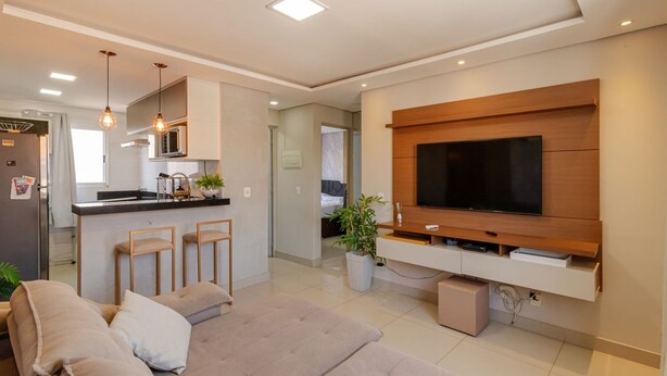 Een moderne woonkamer met een grote televisie, een bank en een keukenhoek met een bar.
