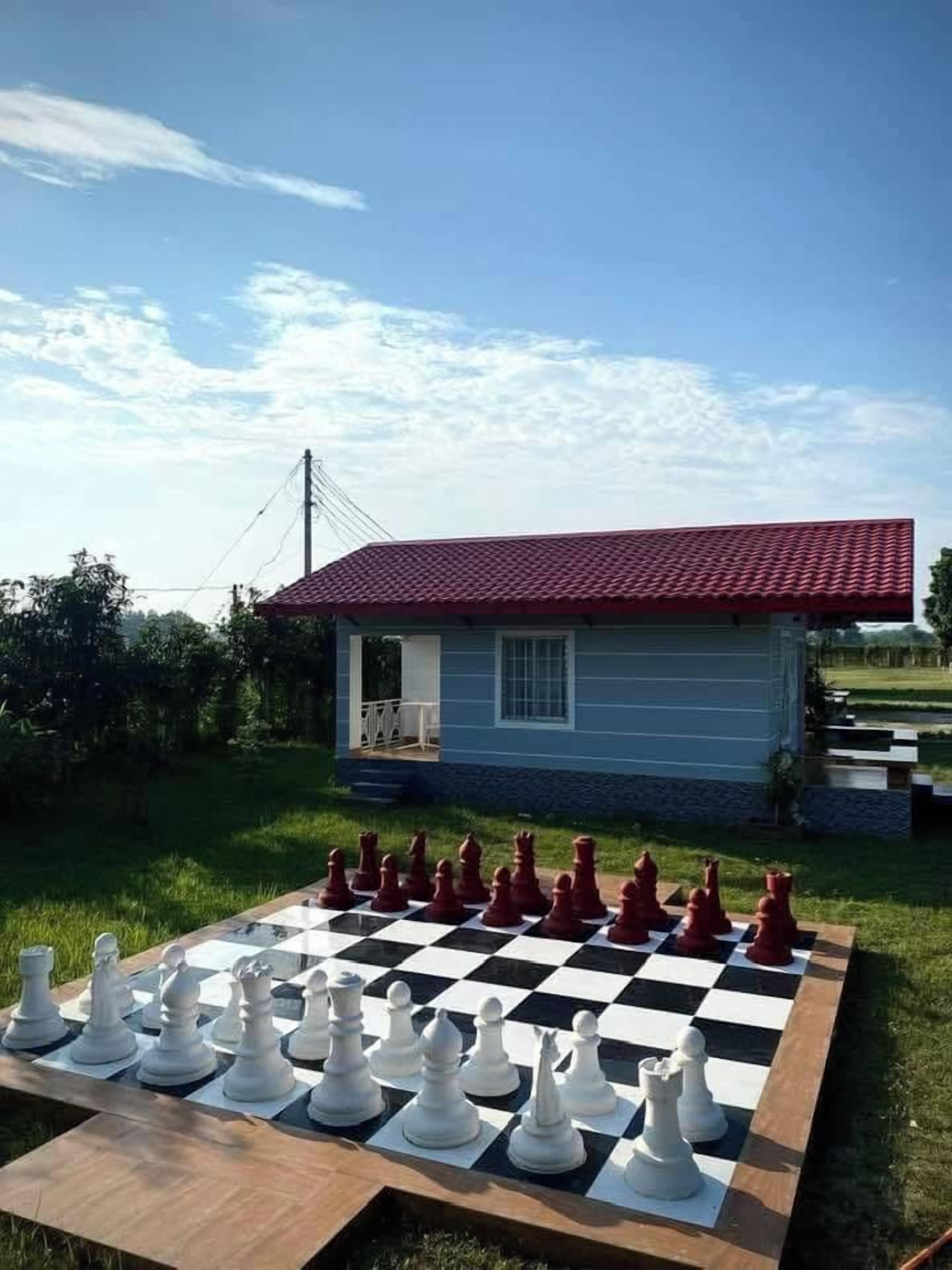 A chessboard set outdoors with a house in the background.