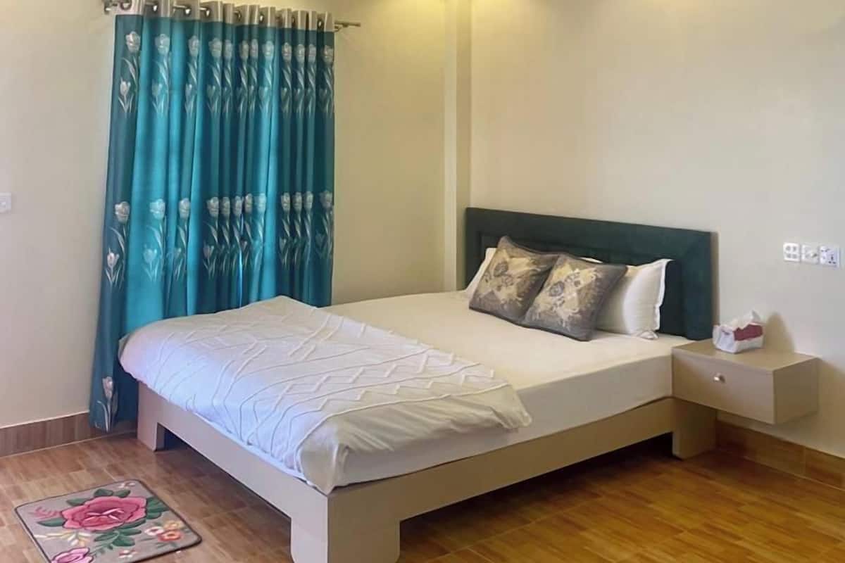 A bedroom with a bed, nightstand, curtains, and a ceiling fan.
