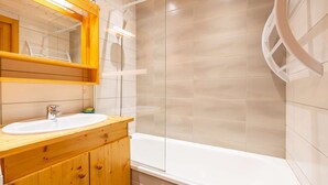 A modern bathroom with a wooden vanity, a white sink, and a bathtub. - Loges A : Grande terrasse à 50m des pistes. (LE GRAND BORNAND)
