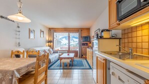 A cozy kitchen with wooden cabinets, a microwave, and a dishwasher. - Loges A : Grande terrasse à 50m des pistes. (LE GRAND BORNAND)
