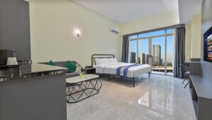 Een moderne hotelkamer met een bed, een bureau, een stoel, een klein tafeltje en uitzicht op de stad.