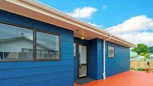 Un edificio azul con una terraza de madera, una puerta y una ventana.