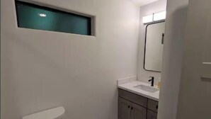 Et lille, moderne badeværelse med toilet, vask og spejl.