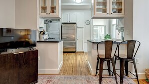 A modern kitchen with white cabinetry, stainless steel appliances, and a built-in island with bar stools. - Capitol Hill, 3 Apartments, 1 House, Free Parking (Washington)