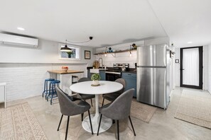 Eine moderne Küche mit einer zentralen Kochinsel, Edelstahlgeräten und einem Essbereich mit rundem Tisch und Stühlen.