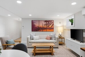 Ein modernes Wohnzimmer mit einer Couch, Couchtisch, Fernseher und Kunstwerken.