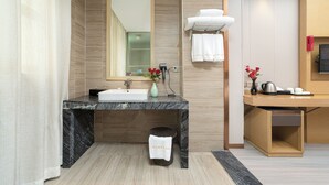 Une salle de bain moderne avec un lavabo en marbre, un miroir, un porte-serviettes et une petite poubelle.