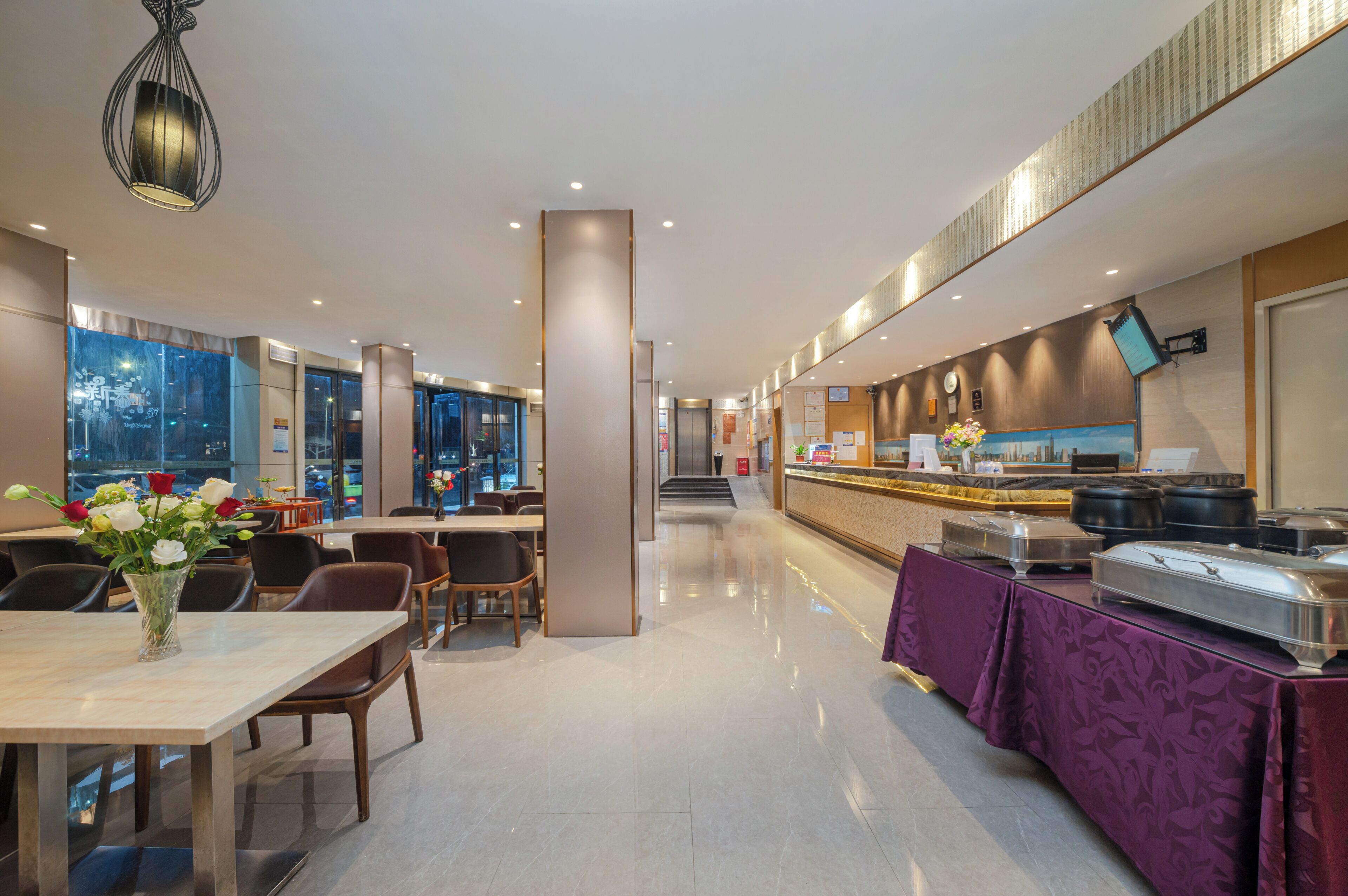 A modern hotel lobby with a reception desk, seating area, and a buffet.