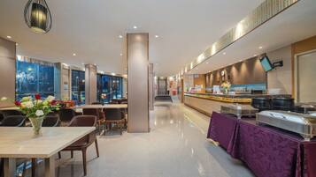 A modern hotel lobby with a reception desk, seating area, and a buffet.