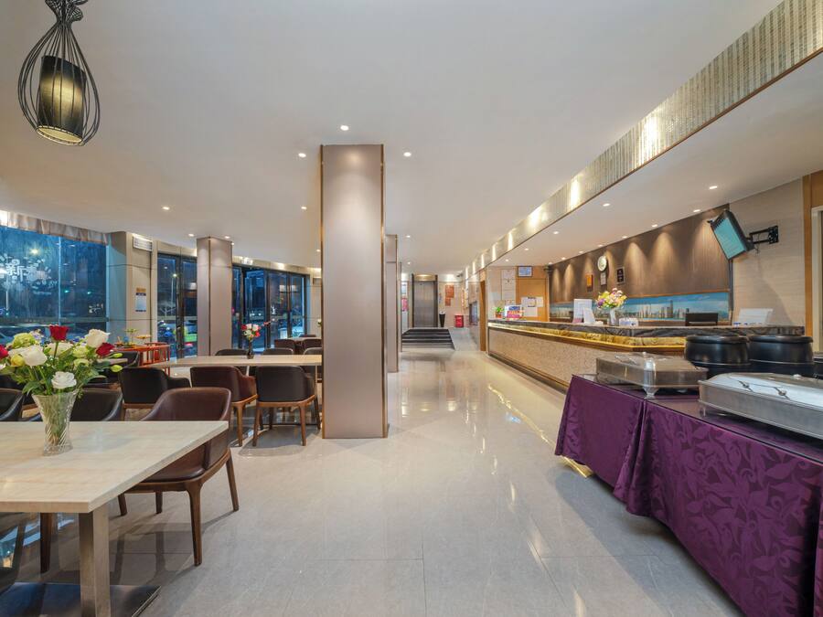 Un hall d’hôtel moderne comprenant un comptoir d’accueil, un espace salon et un buffet.