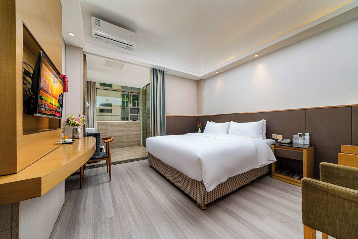 Ein Hotelzimmer mit Bett, Nachttisch, Stuhl, Schreibtisch und Fernseher.