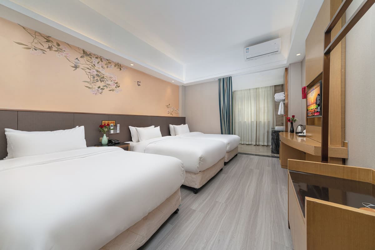 Ein Hotelzimmer mit zwei Betten, einem Schreibtisch, einem Spiegel und einer Wandklimaanlage.