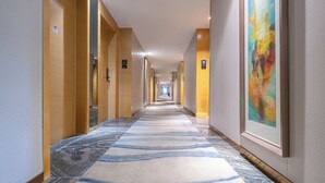 Un couloir d’hôtel, avec un long passage, des portes des deux côtés et un sol recouvert de moquette.