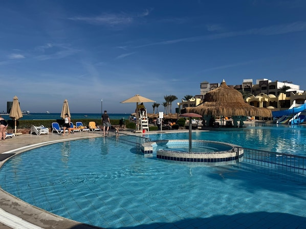 Un espace piscine avec des chaises longues, un toboggan et une vue sur l’océan.