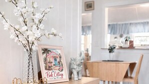 Eine Holztresen mit einem gerahmten Bild, einer Vase mit weißen Blumen und Korbwäsche.