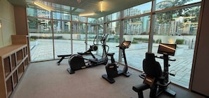 Een moderne sportschool met cardioapparaten, grote ramen en uitzicht op de stad.
