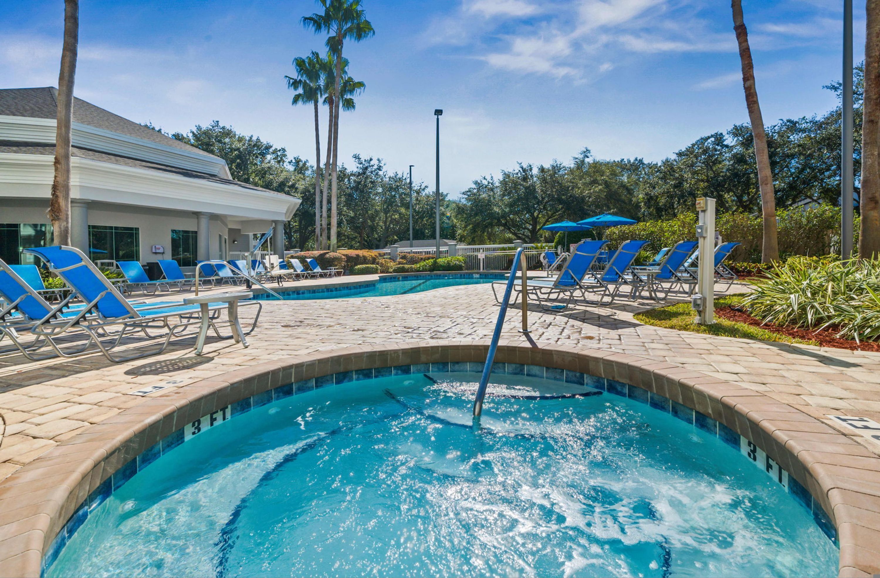 A swimming pool with lounge chairs and a building in the background.