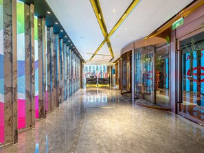 Un moderno vestíbulo de hotel con piso de mármol reflectante, una recepción y escaparates de vidrio.