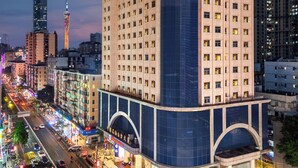 Korkea hotellirakennus, jossa on huomiota herättävä kupolikatto ja suuri lasijulkisivu. Se sijaitsee vilkkaalla kaupunkialueella, ja taustalla näkyy vilkas liikenne sekä muita rakennuksia.