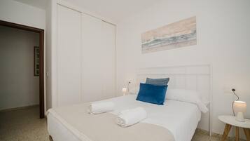 Een hotelkamer met een bed, een nachtkastje, een aan de muur hangend schilderij en een deur.