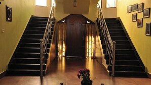 Eine Treppe mit einer Holztür am oberen Ende, gesäumt von zwei Wänden mit eingekachelten Bildern.