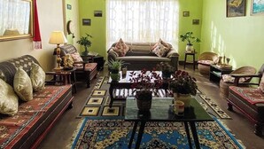 Ein Wohnzimmer mit einer Couch, Sesseln, einem Couchtisch und einem gemusterten Teppich.